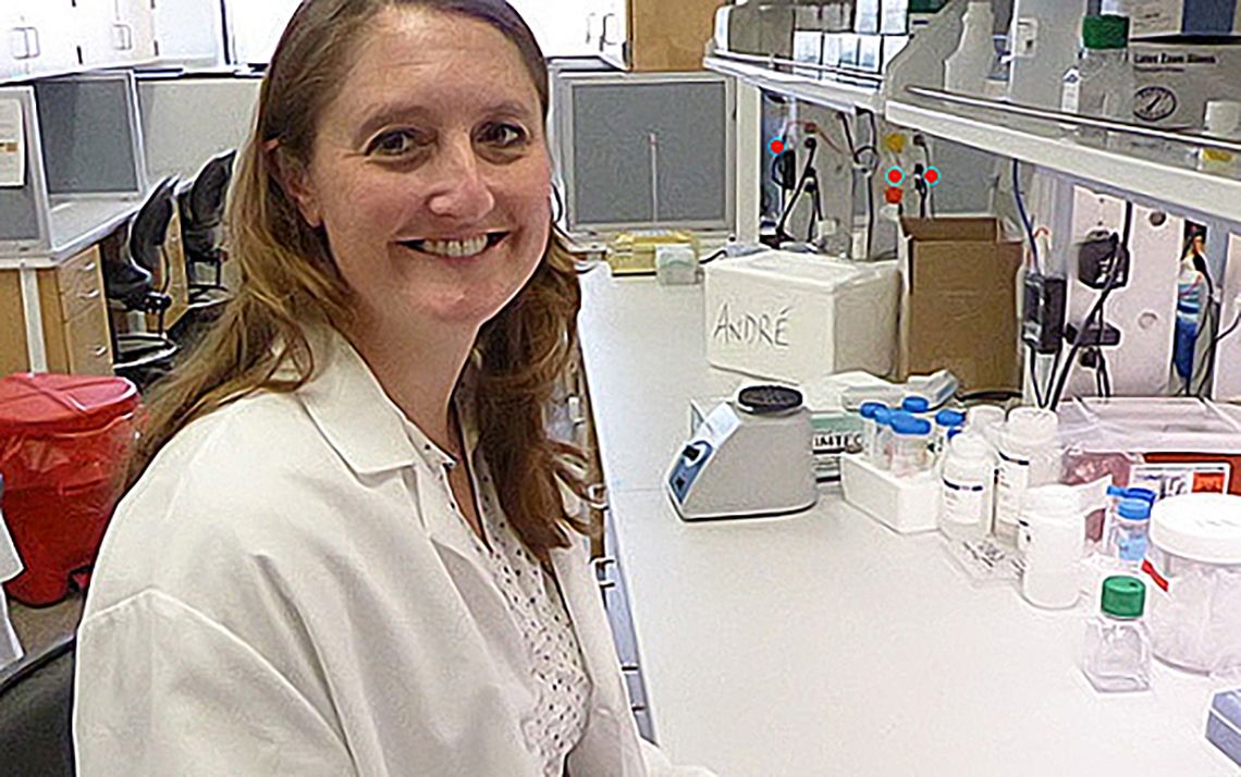 Female lab member smiling, wearing a white coat